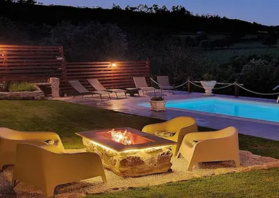 a backyard with a fire pit and chairs next to a pool at Cozy Galician Stone Farmhouse with Fireplaces and Pool in Santo Tomé