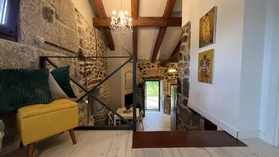 a living room with a yellow chair and a stone wall at Cozy Galician Stone Farmhouse with Fireplaces and Pool in Santo Tomé