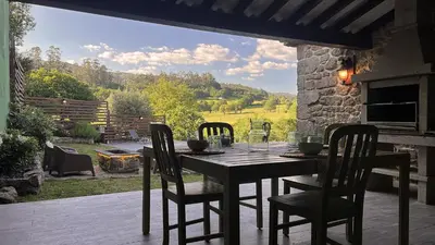 a table and chairs on a patio with a view at Cozy Galician Stone Farmhouse with Fireplaces and Pool in Santo Tomé
