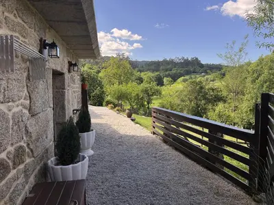 a stone building with a bench and a fence at Cozy Galician Stone Farmhouse with Fireplaces and Pool in Santo Tomé