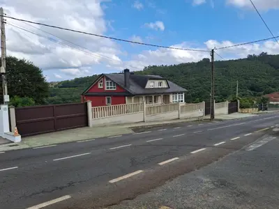 a red house with a fence on the side of a road at Grenxo in Santiago de Compostela