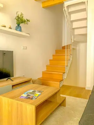 a living room with wooden stairs and a table at Viveiro Dreams in Viveiro