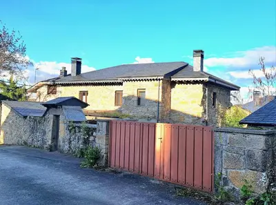 a house with a red gate and a stone wall at Casa El Filandar in Ríonegrito