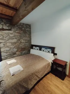 a bedroom with a bed and a stone wall at Casa Rural Borrenes las Médulas in Borrenes