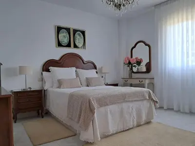 a white bedroom with a large bed and a chandelier at Casa vacacional amplia in Carracedo