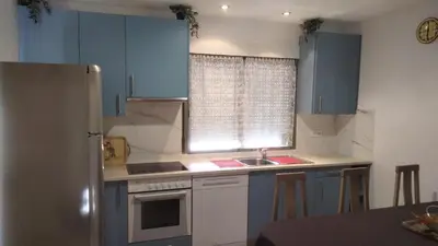 a kitchen with blue cabinets and a sink and a refrigerator at Apartamentos La Fuente Ribadeo in Ribadeo