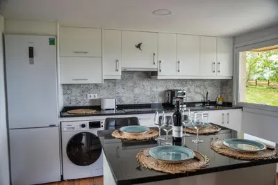 a kitchen with white cabinets and a table with wine glasses at Esperanza de a Trabe in Atrave