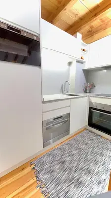 a kitchen with white cabinets and a rug on the floor at The Cliffs - Casa Catuxa in Viveiro