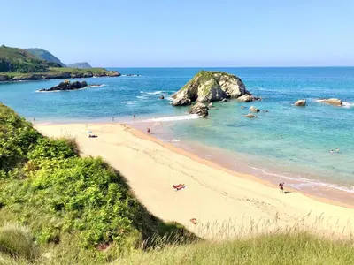 a beach with people swimming in the ocean at The Cliffs - Casa Catuxa in Viveiro