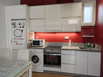 a kitchen with white cabinets and a washer and dryer at Casa Merteira in Ourense