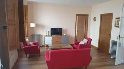 a living room with red chairs and a table and a tv at Casa San Amaro in San Amaro