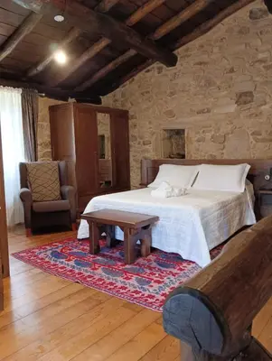 a bedroom with a bed and a table and a chair at Lareira rural apartamento Ribeira Sacra Chantada in Chantada