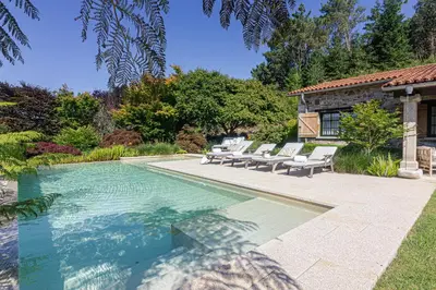 a swimming pool with chairs and a house at Elysian Villa in Miño