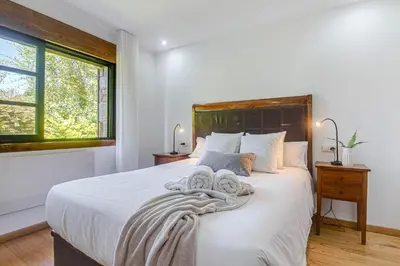 a bedroom with a white bed with a wooden headboard at Elysian Villa in Miño