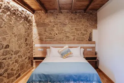 a bedroom with a bed with a stone wall at Tres Portas in Licín