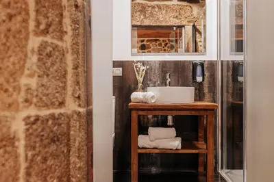 a bathroom with a sink and a shelf with towels at Tres Portas in Licín