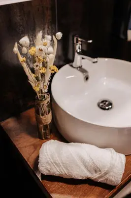 a bathroom sink with a vase of flowers and a towel at Tres Portas in Licín