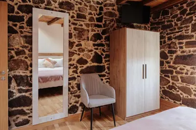 a bedroom with a mirror and a chair in a stone wall at Tres Portas in Licín