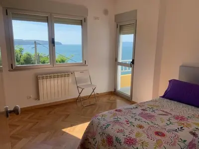 a bedroom with a bed and a chair and windows at Piso Miño con vistas in Miño
