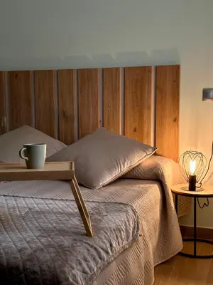 a bed with a wooden headboard with a table on it at Ensueño in Molinaseca