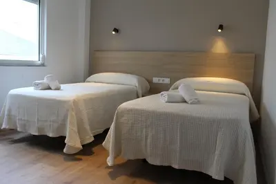 two beds with white linens in a room at Apartamentos Rego Foz in Foz