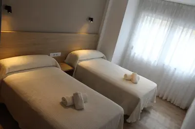 two beds in a hotel room with towels on them at Apartamentos Rego Foz in Foz