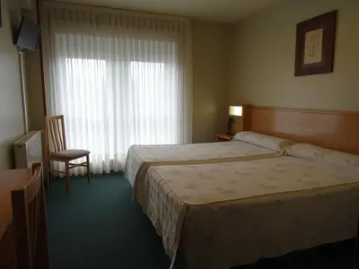 a hotel room with a bed and a chair and a window at Hotel Akelarre in Santiago de Compostela