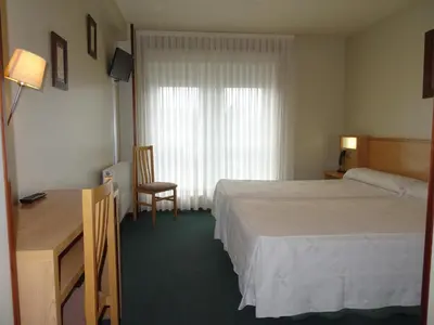 a hotel room with a bed and a desk and a window at Hotel Akelarre in Santiago de Compostela