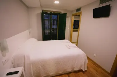 a bedroom with a white bed and a television at Hospederia Tarela in Santiago de Compostela