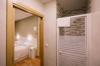 a small bedroom with a bed and a mirror at Hospederia Tarela in Santiago de Compostela