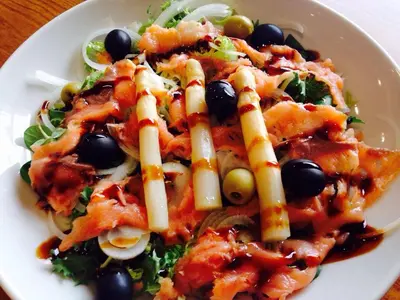 a white plate with a salad with black olives at Hospederia Tarela in Santiago de Compostela