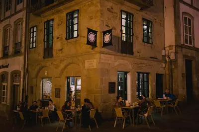 a group of people sitting at tables in front of a building at Hospederia Tarela in Santiago de Compostela