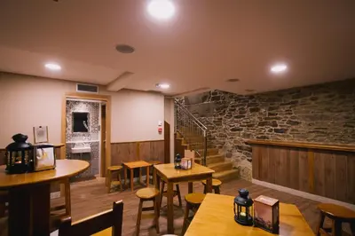a restaurant with tables and chairs and a stone wall at Hospederia Tarela in Santiago de Compostela