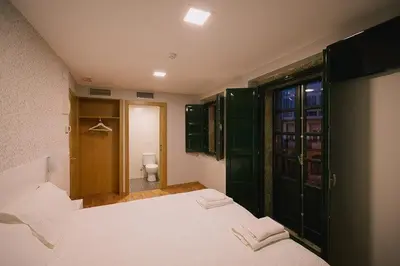 a bedroom with a large white bed and a bathroom at Hospederia Tarela in Santiago de Compostela
