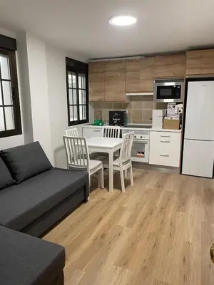 a living room with a couch and a table and a kitchen at Apartamentos Lavandeira by beBalmy in Viveiro