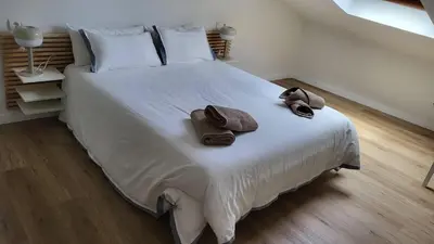 a bedroom with a large white bed with two hats and towels at Apartamentos Lavandeira by beBalmy in Viveiro