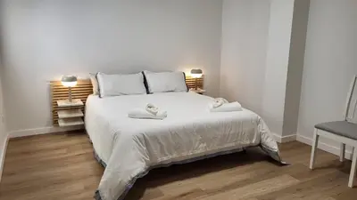 a bedroom with a white bed with two towels on it at Apartamentos Lavandeira by beBalmy in Viveiro