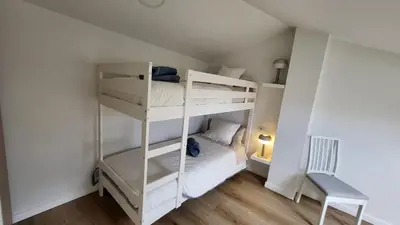 a bedroom with two bunk beds and a chair at Apartamentos Lavandeira by beBalmy in Viveiro