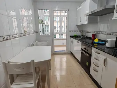 a white kitchen with a table and a sink at Os Garitos in Ribadeo