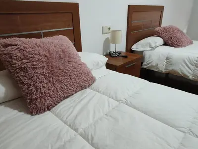 a bedroom with two beds with white sheets and purple pillows at Os Garitos in Ribadeo