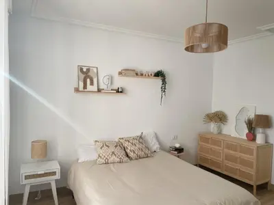 a white bedroom with a bed and a wooden dresser at A Finca Da Toñita in Ribadavia