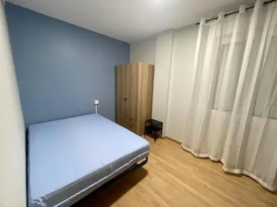 a bedroom with a white bed and a blue wall at Piso Turístico Felipe Herce in Ponferrada