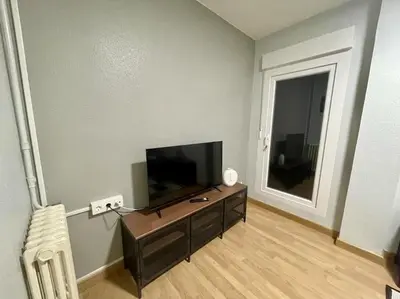 a living room with a flat screen tv and a chair at Piso Turístico Felipe Herce in Ponferrada
