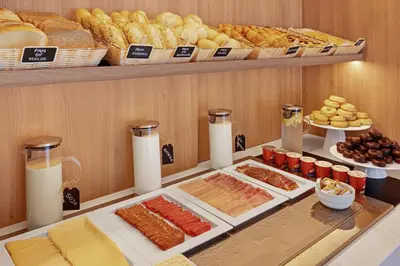 a buffet with different types of bread and pastries at B&B HOTEL Santiago Milladoiro in Milladoiro