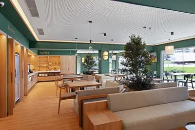 a lobby with couches and tables in a cafeteria at B&B HOTEL Santiago Milladoiro in Milladoiro