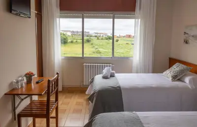 a room with two beds and a table and a window at Pensión A Codeseira Melide in Melide