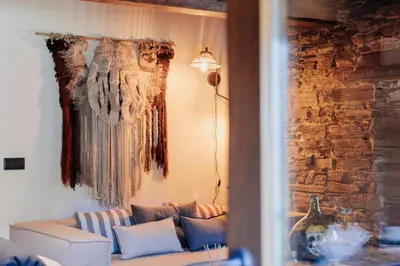 a living room with a couch and a stone wall at Casa do Corral in Hospital