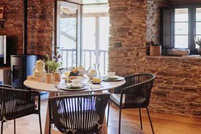 a table and chairs in a room with a brick wall at Casa do Corral in Hospital