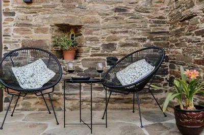 two chairs and a table in front of a stone wall at Casa do Corral in Hospital