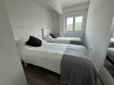 two beds in a white room with a window at Oktheway Caldas Centro in Caldas de Reis